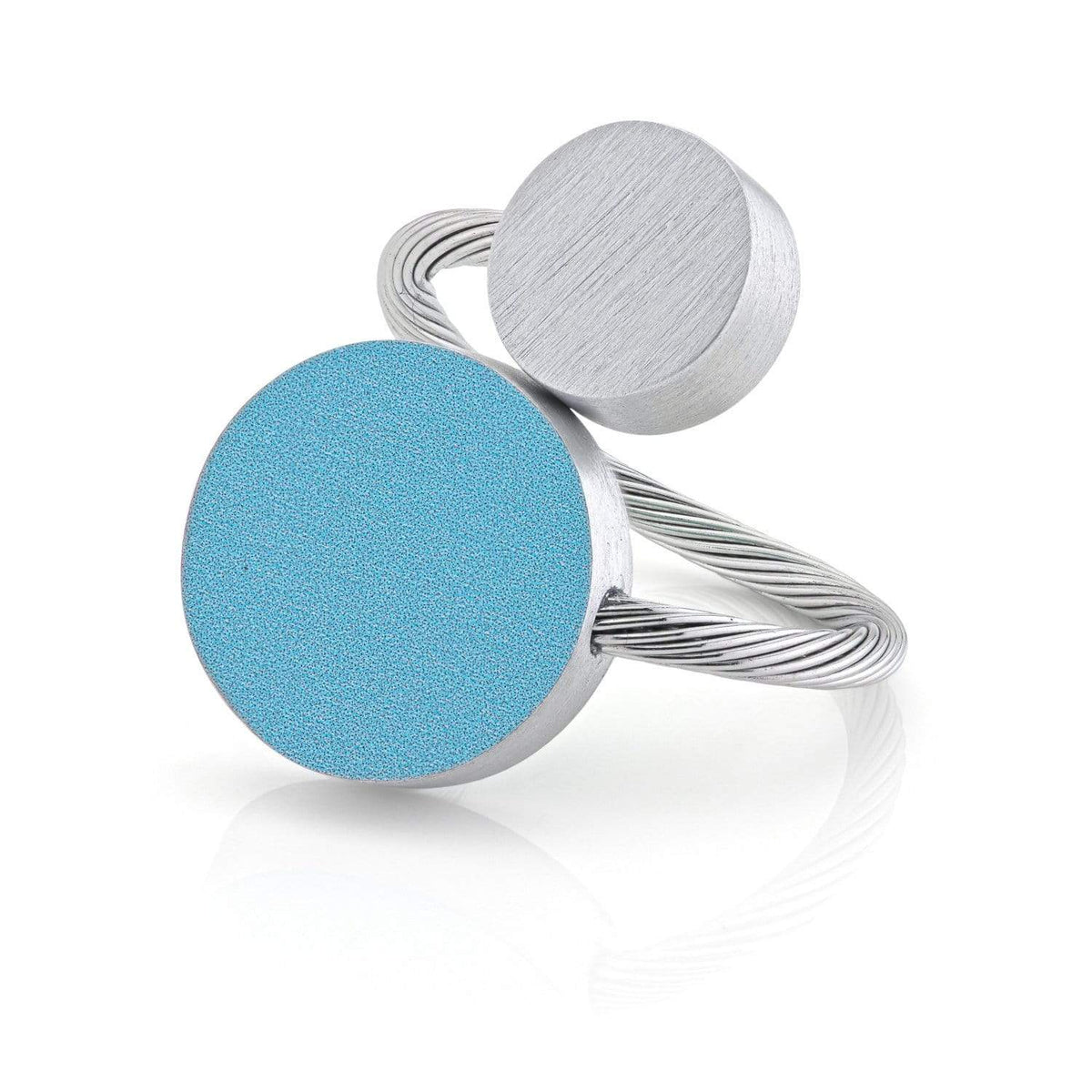 Anillo con dos formas redondas, una azul mate y otra plateada, sobre una base de alambre.