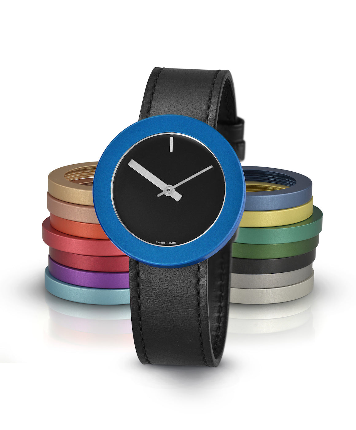 Reloj con esfera negra, correa de cuero negra y bisel azul, acompañado de varios anillos de colores.