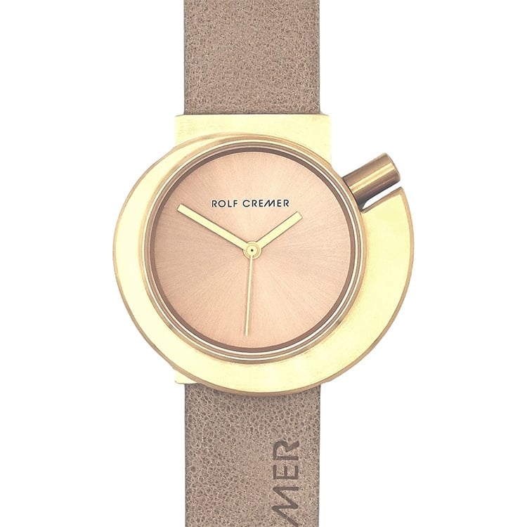 Reloj Rolf Cremer con esfera dorada, correa de cuero beige y diseño circular moderno.