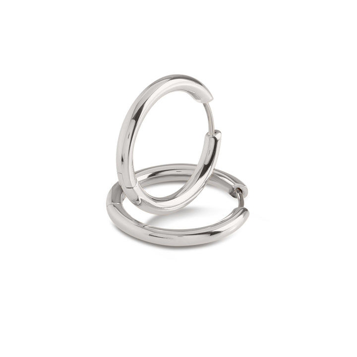 Een paar Boccia Titanium Oorringen 05072-01 oorbellen, gemaakt van glanzend zilver met een glad ontwerp, worden getoond op een witte achtergrond; één oorbel staat rechtop, terwijl de andere plat ligt.