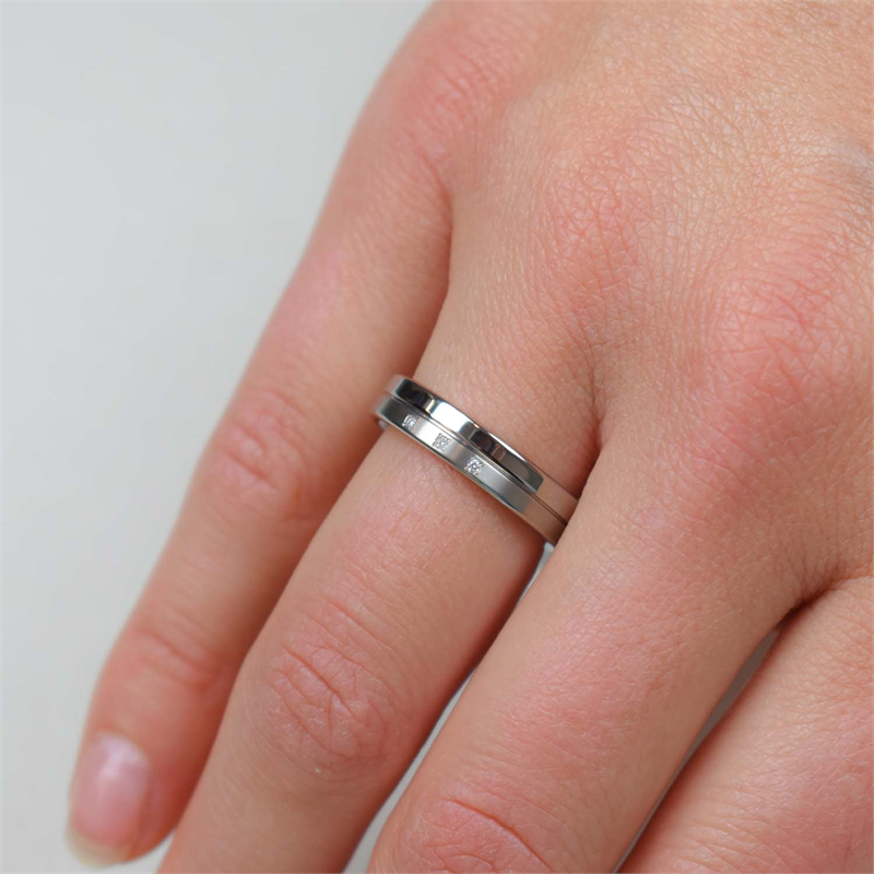 Een close-up van een hand met twee zilveren ringen, waaronder de Boccia Titanium Ring dia 3/0.015 - 0129-03 van Boccia, om de ringvinger tegen een effen, lichte achtergrond.