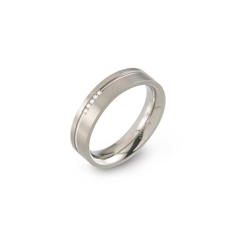 Anillo de titanio con tres pequeñas piedras brillantes y acabado pulido.