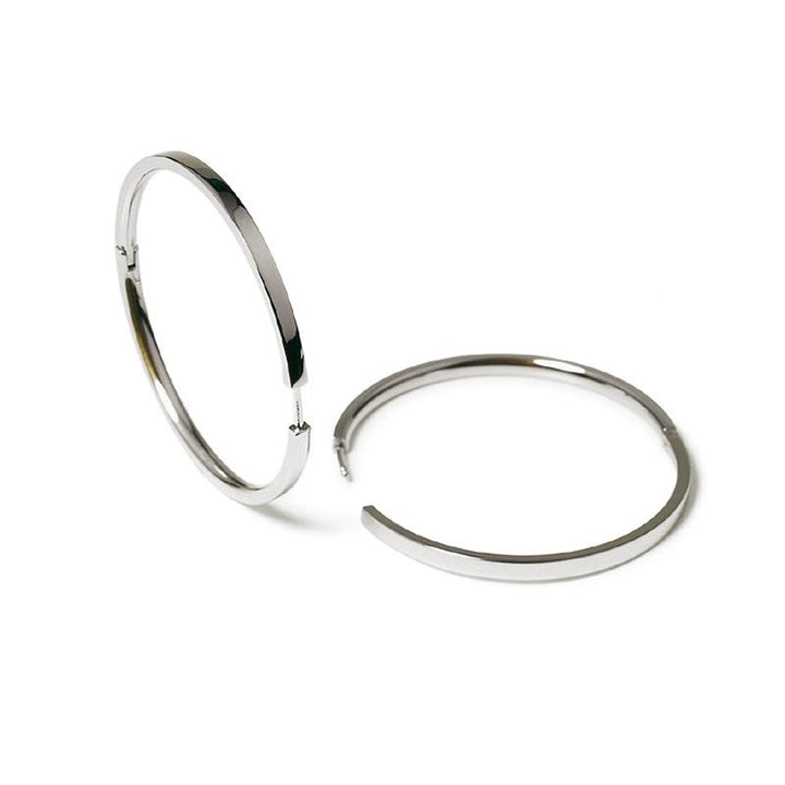 Twee grote, glanzende Boccia Titanium Oorringen 0508-03 worden getoond op een witte achtergrond. De ene staat rechtop en de andere ligt plat, beide benadrukken een eenvoudig, minimalistisch ontwerp van Boccia.