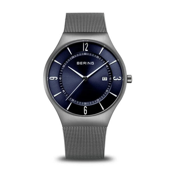 Reloj con esfera azul, correa de malla metálica gris y detalles en plata.