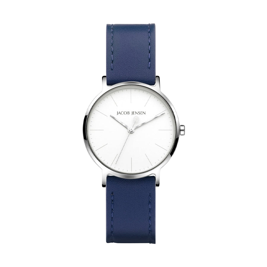 Het Jacob Jensen 173 polshorloge heeft een minimalistisch design met een witte ronde wijzerplaat, zilveren markeringen en twee wijzers. Het heeft een zilveren kast met een blauwe leren band.