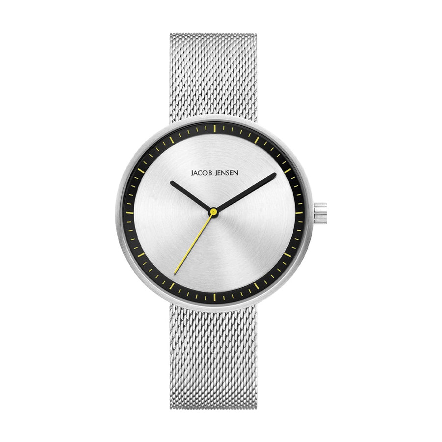 Reloj de esfera plateada con malla de acero inoxidable y detalles amarillos.