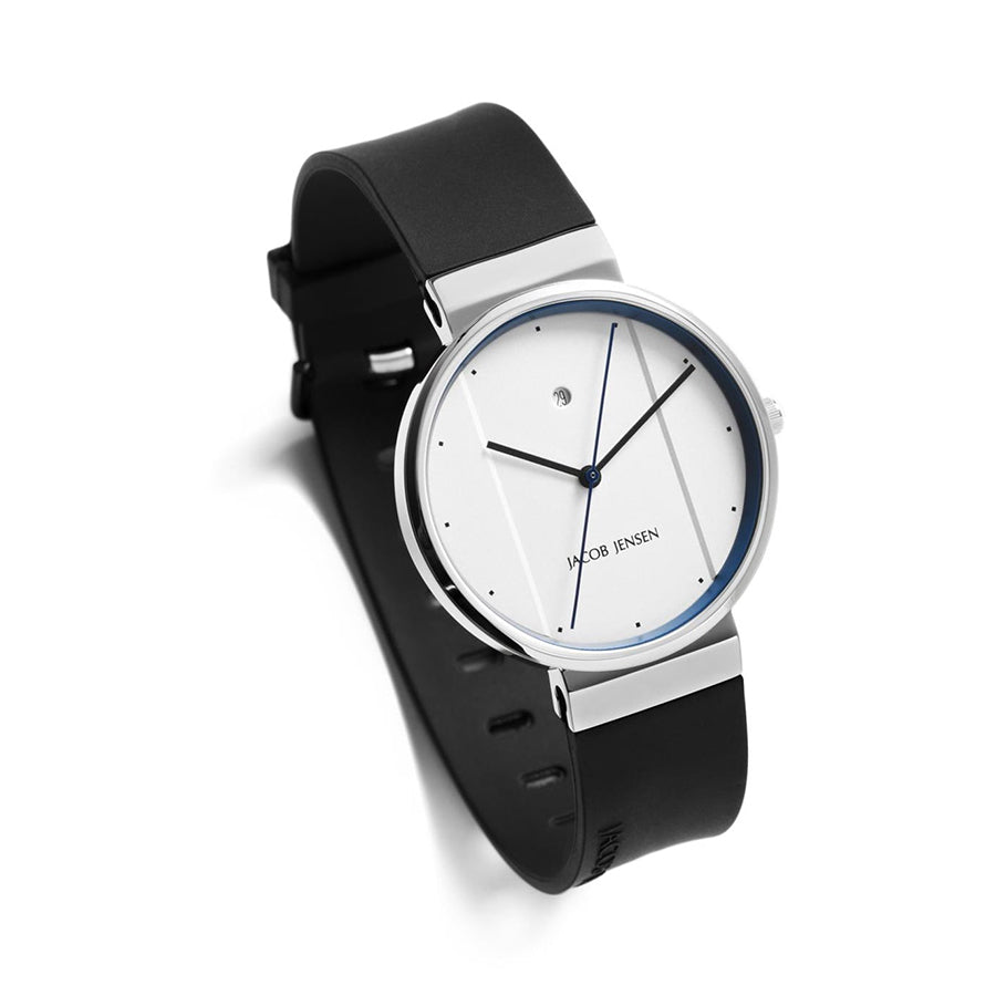 Het Jacob Jensen 750 horloge heeft een strak, minimalistisch design met een witte wijzerplaat, dunne blauwe wijzers en een kleine centrale wijzerplaat. De zwarte leren band past perfect bij de roestvrijstalen behuizing, allemaal aangestuurd door een quartz uurwerk voor moderne elegantie.