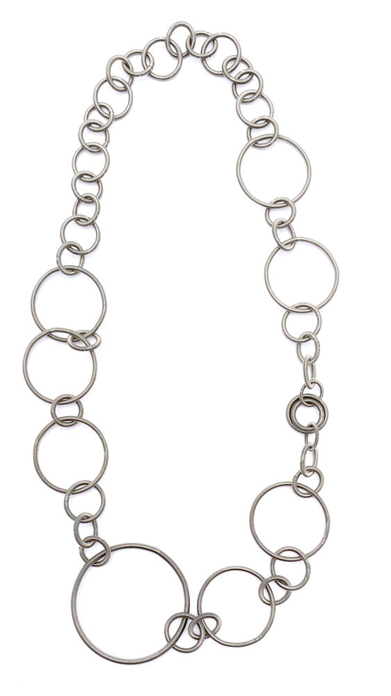Collar de diseño en acero con eslabones circulares de diferentes tamaños.