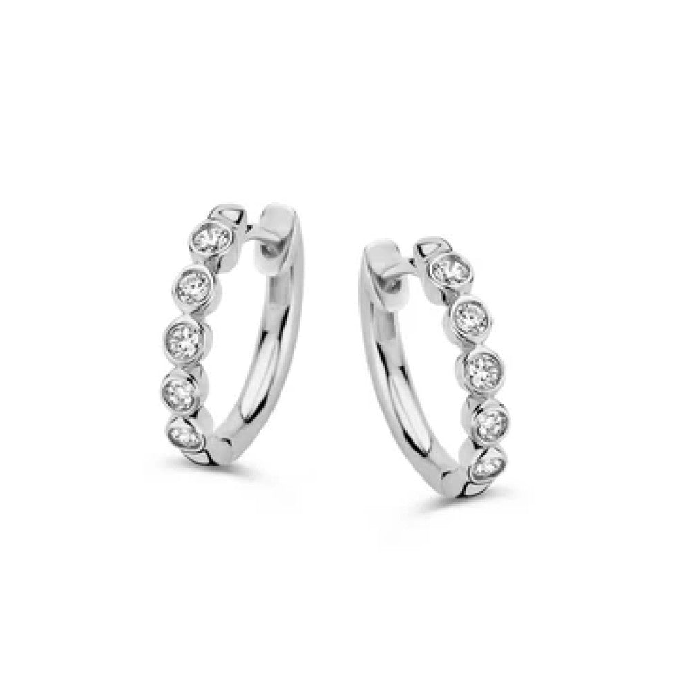 Aros de oro blanco con diamantes, adornados con pequeñas piedras brillantes en un lado.