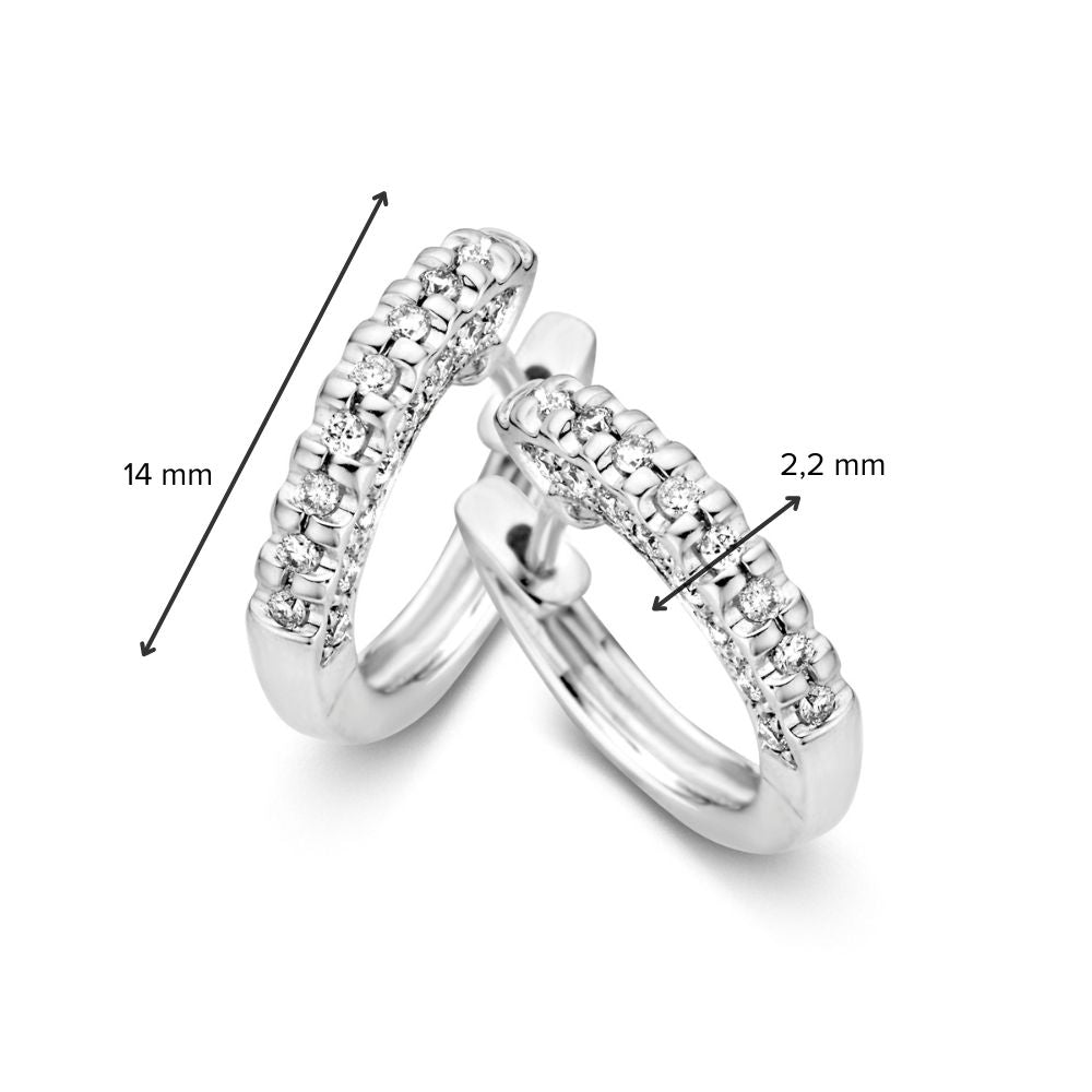 Een paar 14 karaat witgouden oorringen van Excellent Jewelry met diamanten aan de zijkanten (0.30 crt). Eén oorbel staat rechtop, de ander ligt neer. Afmetingen: 14 mm hoog, 2,2 mm breed.