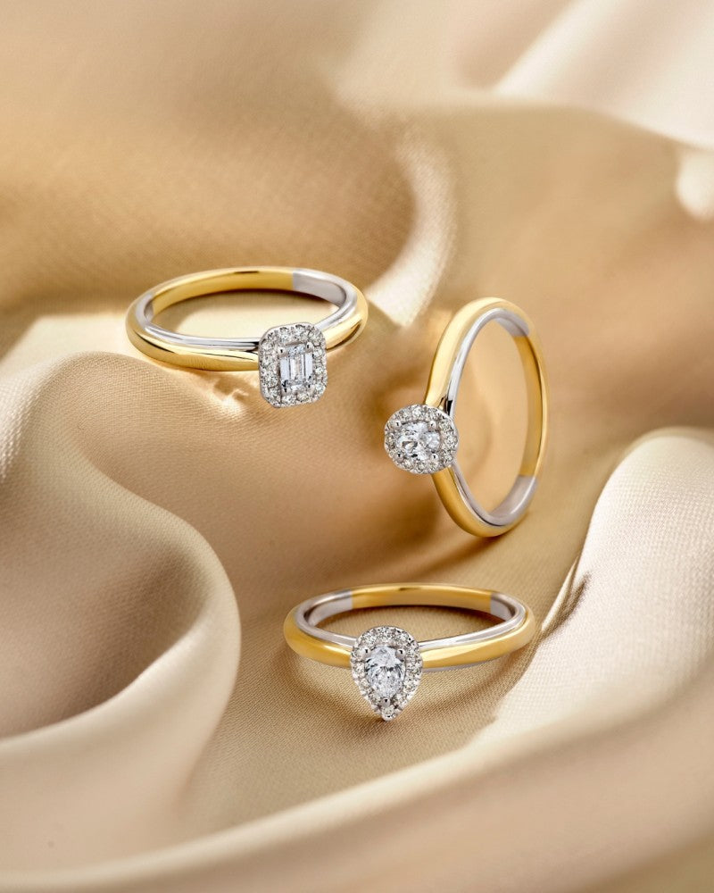 De 14k bicolor gouden ring van Excellent Jewelry heeft een ovaal diamanten hart in een entourage zetting, elegant weergegeven op zacht, beige satijnen stof.