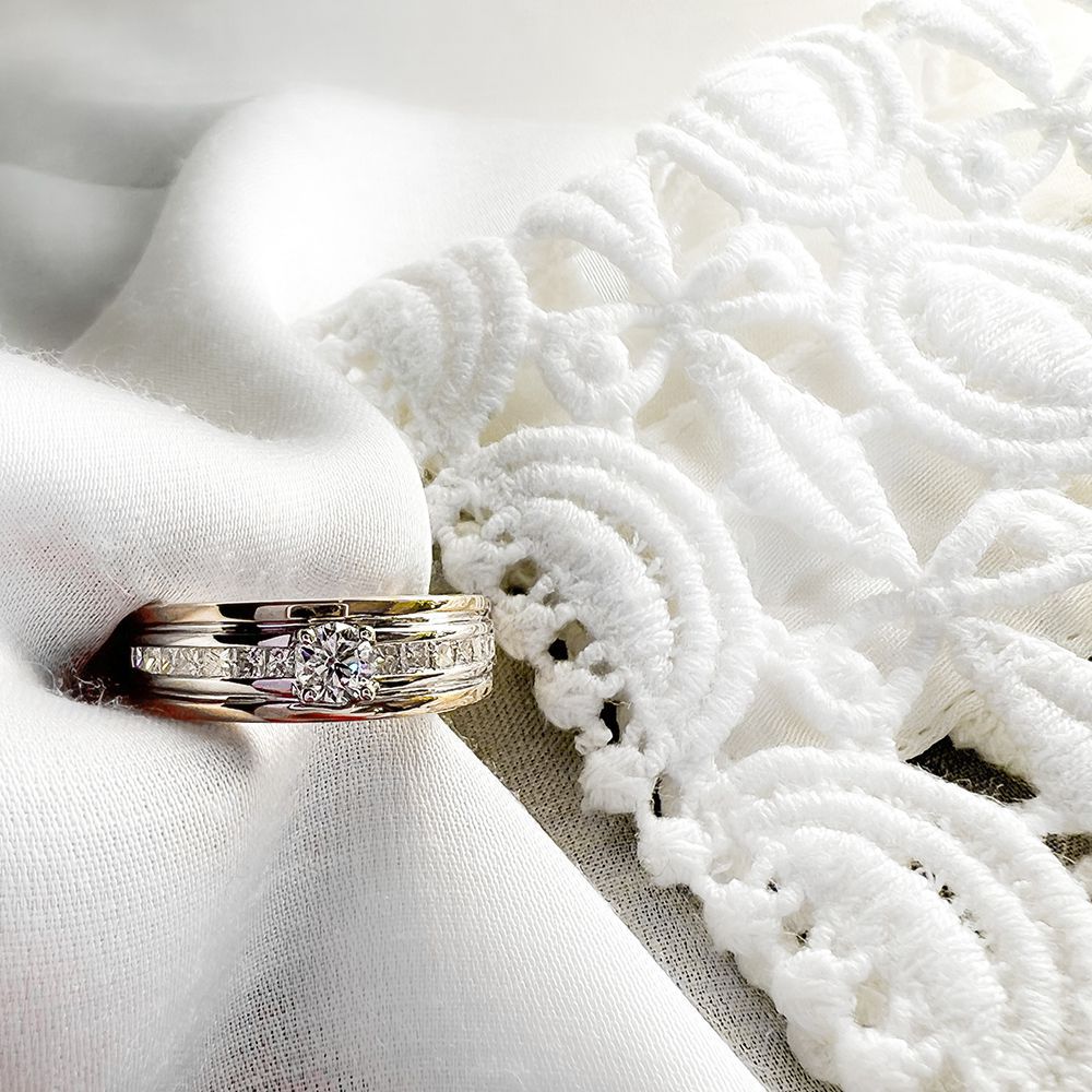 De Elegante damesring geelgouden band met briljant diamant 0.54ct van Excellent Jewelry schittert op witte, reliëf kantstof en straalt elegantie en romantiek uit.