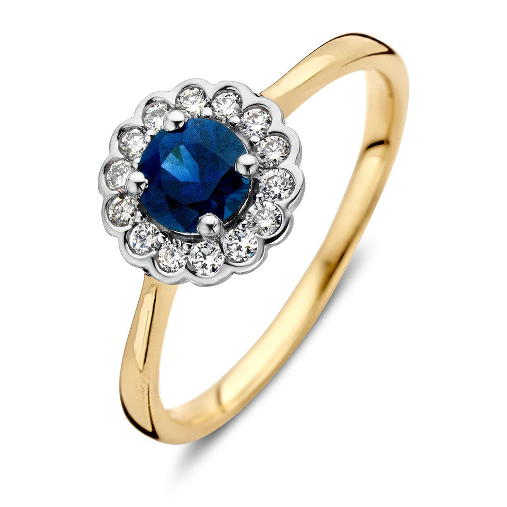 Anillo clásico de oro con zafiro azul redondo y diamantes de 0.18ct en un diseño de flor.