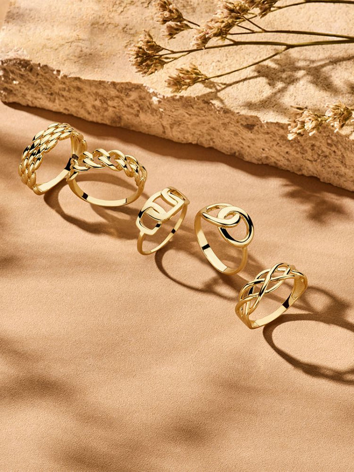 De Geelgouden Damesring van Excellent Jewelry, eenvoudig maar elegant in 14 karaat goud, ligt op een beige ondergrond met zachte schaduwen van dorre planten-de perfecte tijdloze ring voor elke gelegenheid.