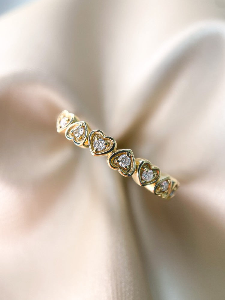 Anillo de banda refinado en oro amarillo con corazones y diamantes de 0.12 crt.