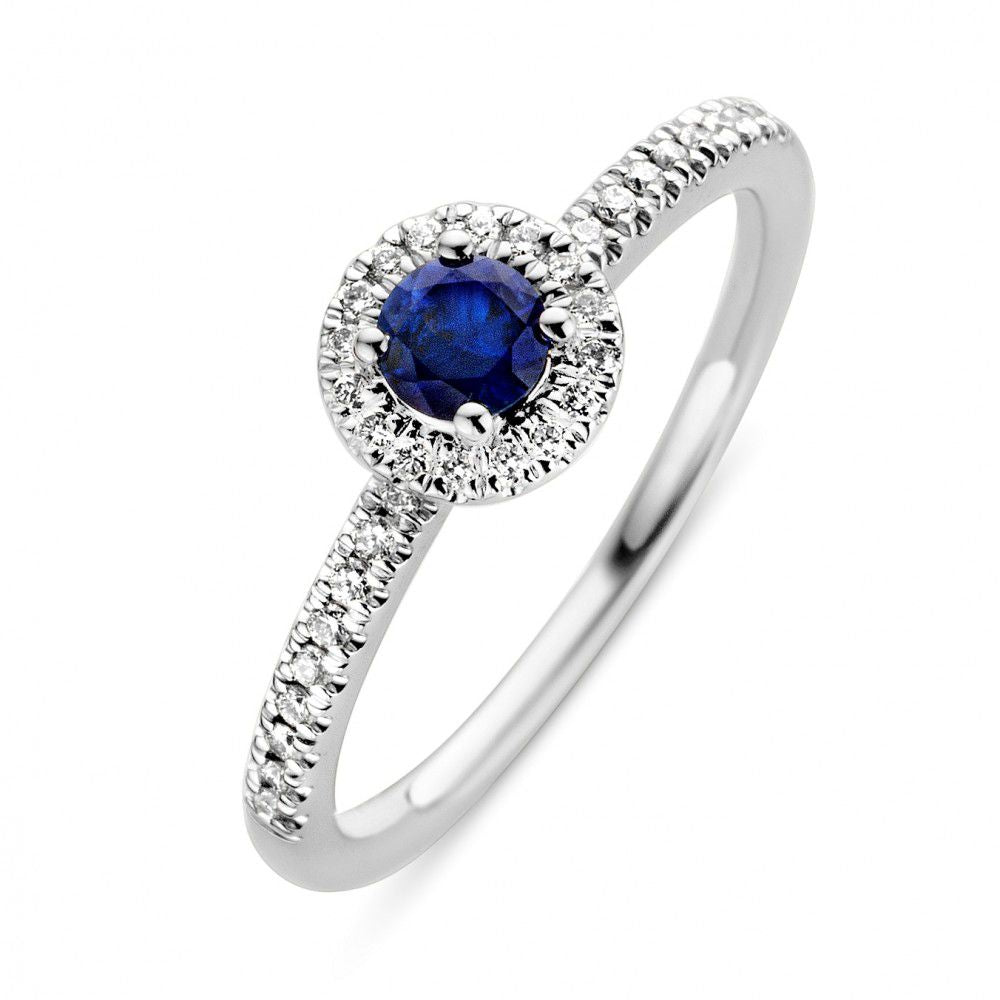 Anillo de oro blanco con zafiro azul en el centro y diamantes alrededor.