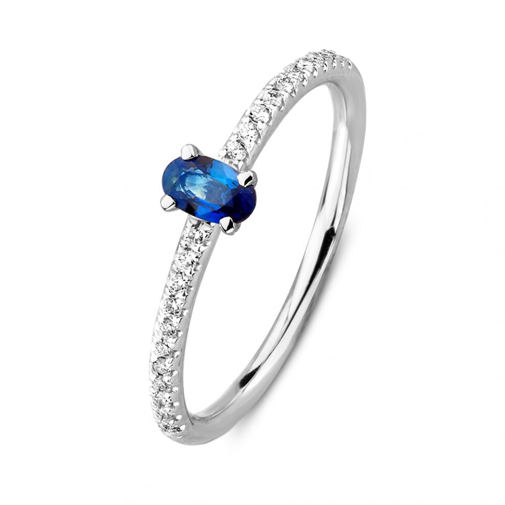 Anillo de oro blanco con un zafiro ovalado y diamantes brillantes en el aro.