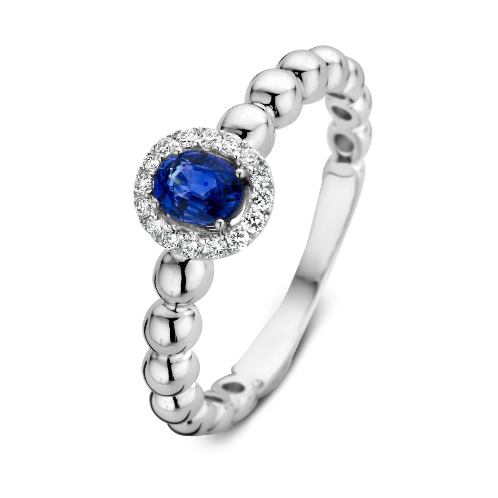 De 14 karaat witgouden rijring van Excellent Jewelry heeft een ovale blauwe saffier centraal, omringd door 0,14 ct fonkelende diamanten.