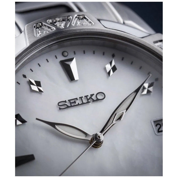 Close-up van een Seiko dameshorloge SKK727P1 met een witte parelmoer wijzerplaat, zilveren uurmarkeringen en wijzers, ruitvormige accenten en nauwkeurig Quartz uurwerk. De datumweergave is gedeeltelijk zichtbaar aan de rechterkant.