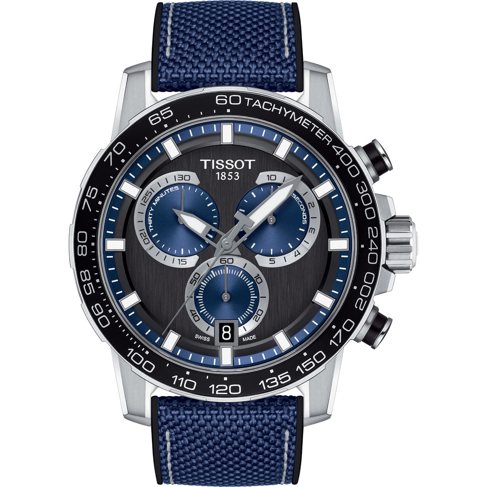 Reloj cronógrafo Tissot con esfera negra y detalles azules, correa de malla azul y caja plateada.