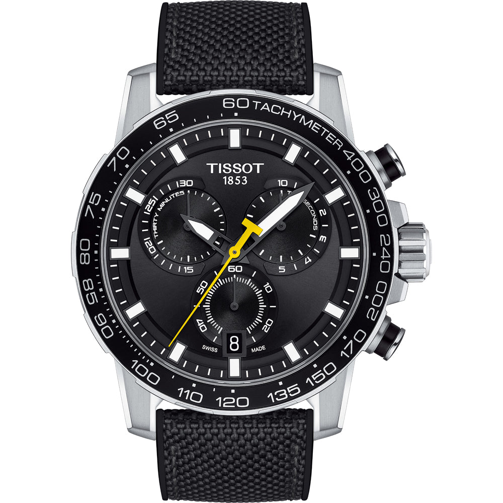 Reloj cronógrafo Tissot con esfera negra, detalles amarillos y correa de tela negra.