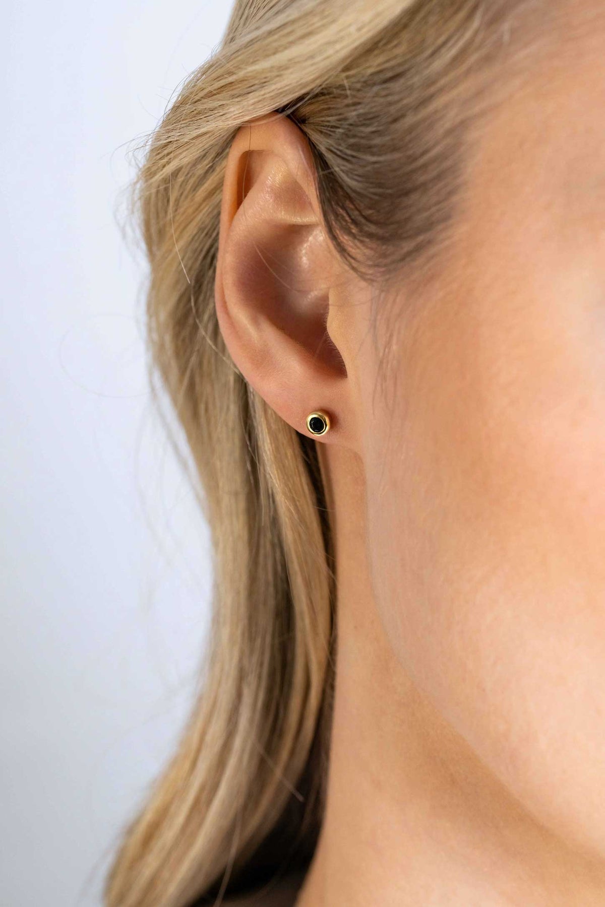 Pendientes de primera puesta chapados en oro con un diseño circular y un detalle central oscuro.