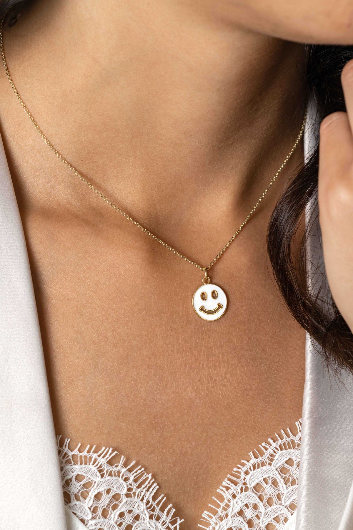 Colgante dorado con forma de sonrisa, suspendido de una cadena delicada.