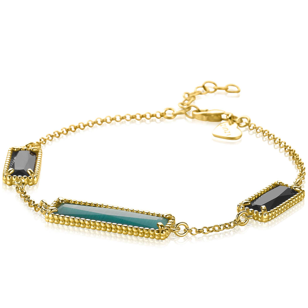 De Zinzi Armband Gold Plated Zia2112 van Zinzi is een gouden, geel vergulde armband met drie blauwgroene en donkergrijze rechthoekige edelsteenachtige versieringen omlijst in goud met kraaldetails. Het bevat een verstelbare ketting en hartvormige bedel.