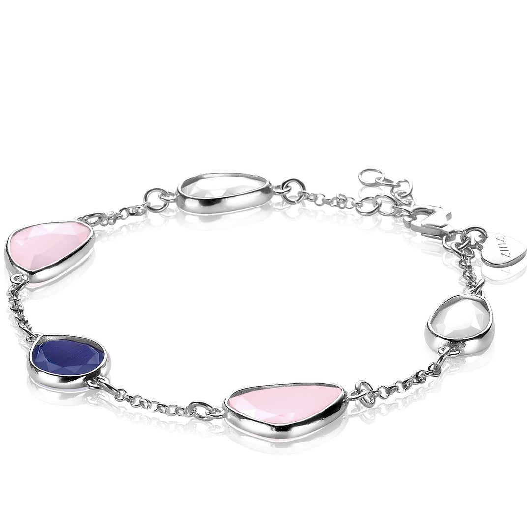 De ZINZI Armband Zilver Zia1998 heeft asymmetrische, bezel-set stenen in levendige blauwe, roze en heldere tinten, verbonden door een delicate zilveren ketting. Een klein gegraveerd label voegt charme toe bij de sluiting.