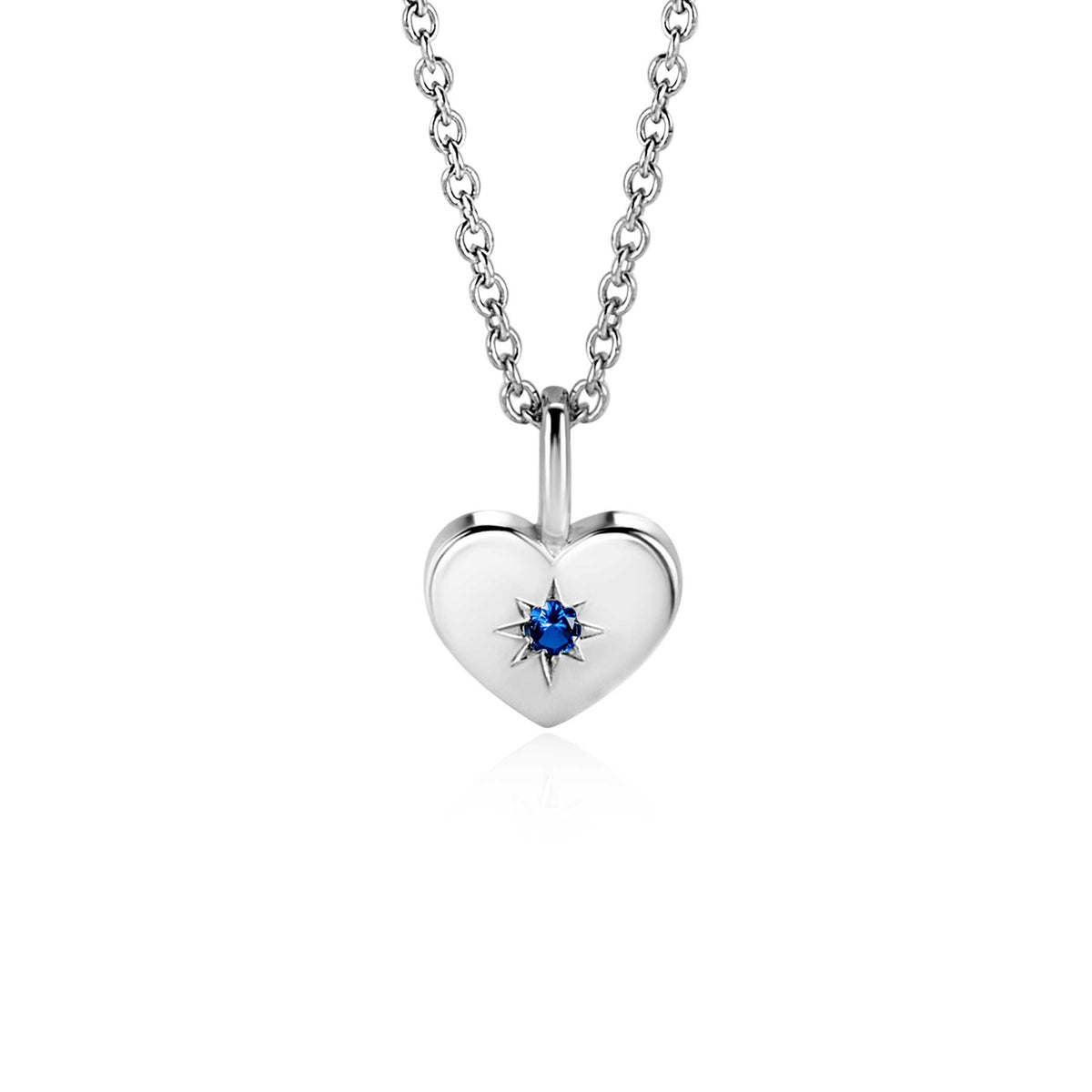 Colgante en forma de corazón de plata con un detalle azul en el centro, suspendido de una cadena.