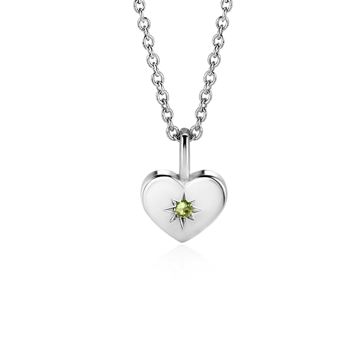 Colgante de corazón plateado con una piedra verde en el centro y cadena plateada.
